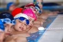 Kinderschwimmen Kinder im Wasser am Beckenrand